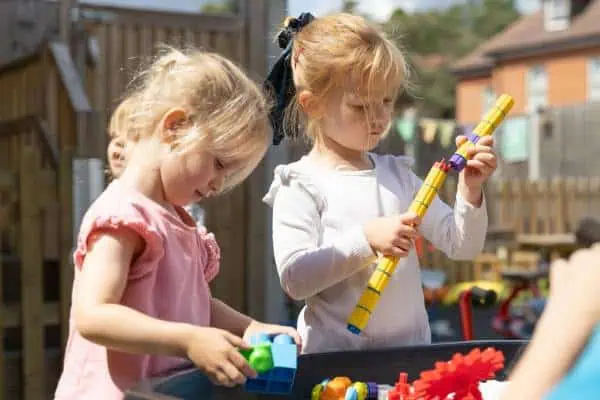 Children playing with toys outdoors at Monkey Puzzle Day Nursery Feltham.