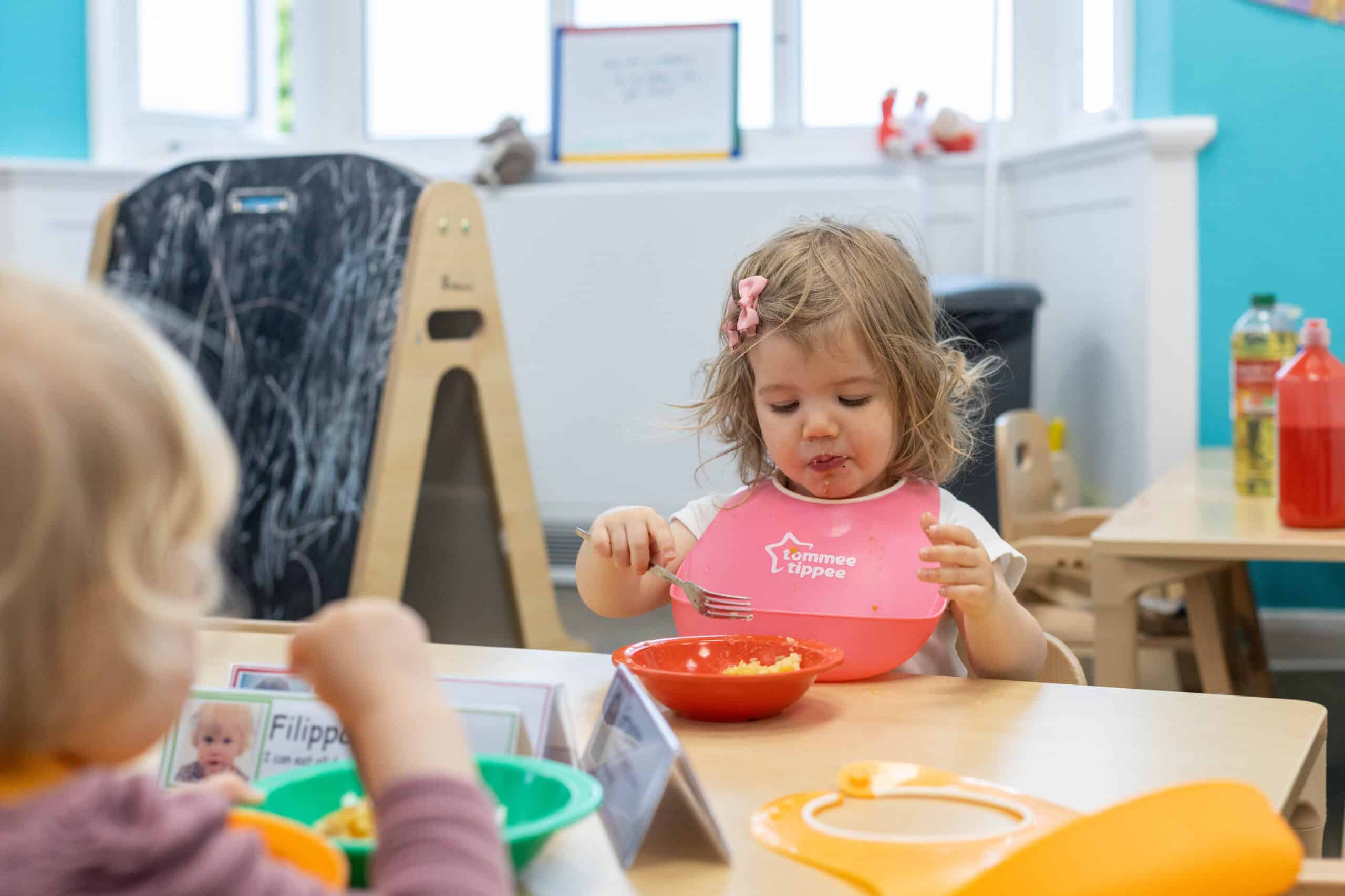 Monkey Puzzle Day Nursery Feltham Young girl eating healthy food at nursery table in Feltham.