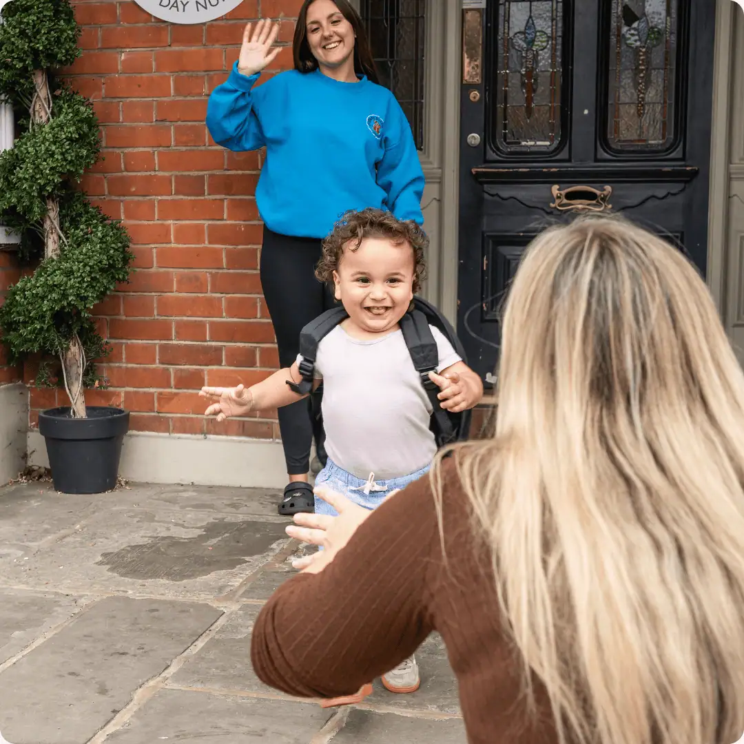 Happy child and staff member outside Monkey Puzzle Feltham nursery.